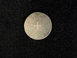 a silver coin with a cross on it on a black surface