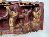 a red and gold sculpture of a boat with people on it