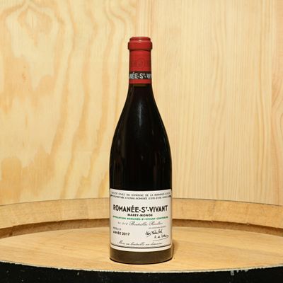 a bottle of wine sitting on top of a barrel
