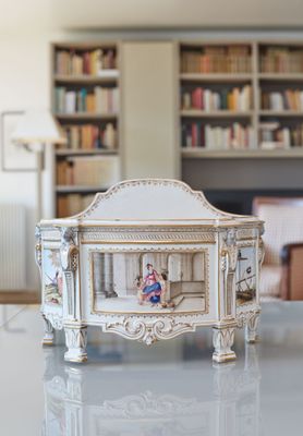 a miniature doll sitting in a miniature crib on a table
