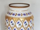 a white and gold vase with blue flowers on it