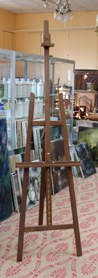 an easel in the middle of a room with pictures on the floor