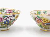 two cups with flowers and birds painted on them on a white surface
