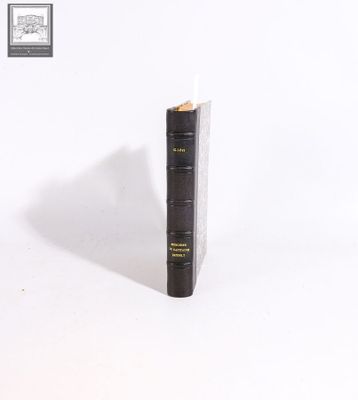 an old black book sitting on top of a white surface