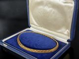an image of a gold bracelet in a blue case on a black surface