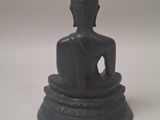 statue of a person sitting in a lotus position on a white surface