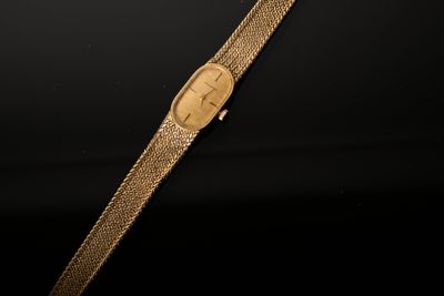 a gold watch on a black surface with a black background