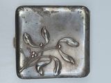 a small silver box with a flower design on it