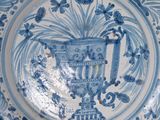 a blue and white plate with a vase on it