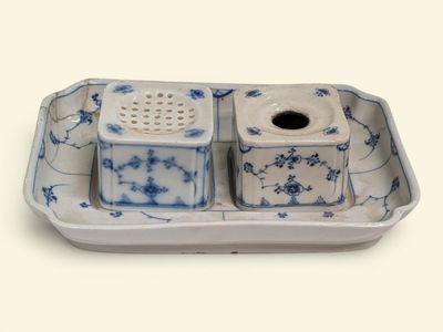 une assiette bleue et blanche sur laquelle sont posés deux salières et poivrières