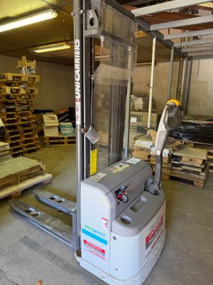 a forklift in a warehouse with pallets of wood