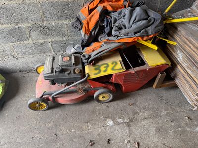 une tondeuse à gazon posée à côté d'un tas de bois