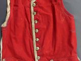 an old red vest with gold trim and buttons on the front