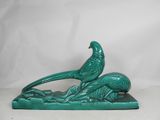 a green statue of a bird sitting on top of a tree branch