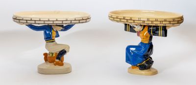deux figurines représentant un homme portant un plateau sur la tête