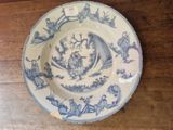 a blue and white plate with a boat and people on it