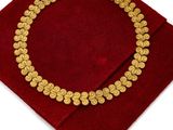 a close up of a gold necklace on a red velvet bag