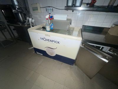 une glacière blanche et bleue sur laquelle est posée une bouteille de produit nettoyant