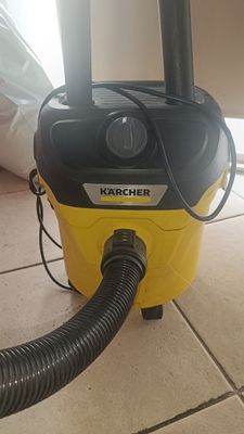 un aspirateur jaune et noir posé sur un sol carrelé près d'une fenêtre