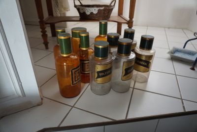 de nombreux flacons de parfum posés sur un sol carrelé