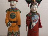 trois figurines en céramique représentant des personnages asiatiques, exposées dans une vitrine