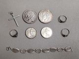 beaucoup de bijoux en argent posés sur une table à côté d'une pièce de monnaie