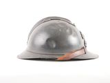 an old helmet with a leather strap on it sitting on top of a white surface