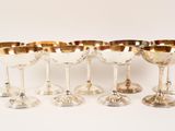 six silver wine glasses with gold rims on a white background