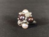 a close up of a ring with pearls on a black surface