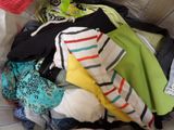a pile of clothes sitting on a bed with a crochet hat on top of it