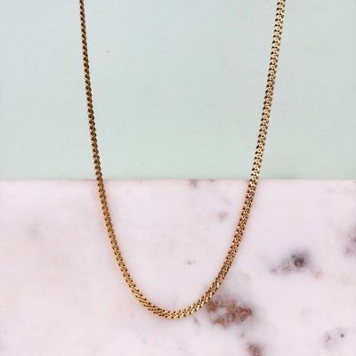 un collier à chaîne en or posé sur un comptoir en marbre