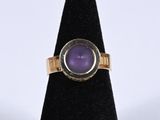 a close up of a ring with a purple stone in it