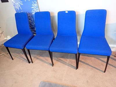 Quatre chaises bleues sont alignées contre un mur dans un salon