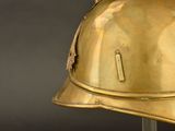 a gold helmet on a metal stand against a black background