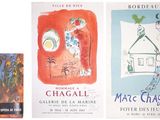 several books are lined up on a white surface, one has a painting of a house and the other has a painting of a cat