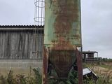 an old rusted metal tower sitting in a field next to a building