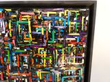 peinture abstraite représentant des carrés multicolores dans un cadre noir accroché à un mur blanc