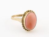 un gros plan d'une bague en or sertie d'un corail ovale