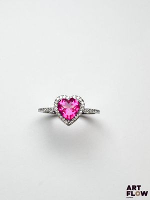 une bague rose en forme de cœur sertie de diamants sur fond blanc