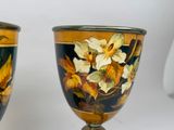 two vases with flowers painted on them sitting on a table