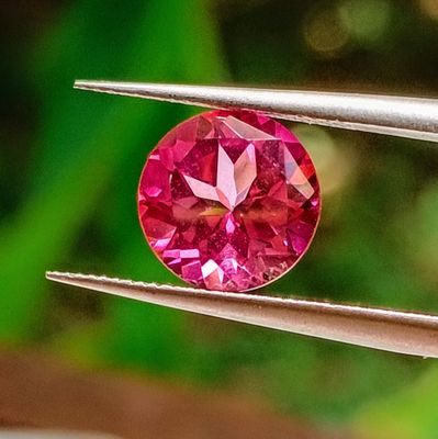 a close up of a pink diamond being held by a pair of pliers