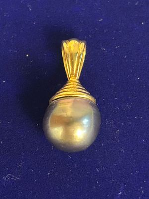 yellow gold pearl pendant on a blue background