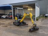 a small yellow excavator parked in front of a building