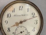 an old pocket watch hanging on a wall next to a clock