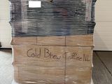 Des cartons de café infusé à froid sont empilés sur une palette dans un entrepôt