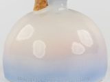 a white vase with a blue flower on top of it