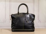 the black leather handbag is sitting on a table in front of a wall