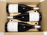 three bottles of wine are in a cardboard box on a table
