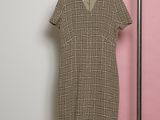 the dress is hanging on a hanger in front of a pink wall