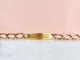 un gros plan sur un bracelet à chaîne en or orné d'une plaque portant un nom